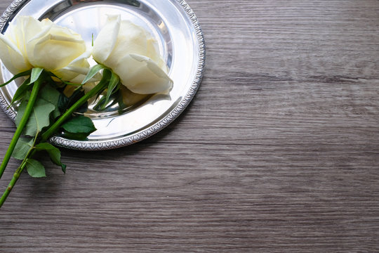White roses on vintage round silver plate on wooden plank floor with copy space for valentine's day wedding ceremony