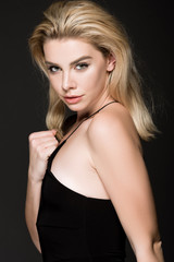 Fototapeta na wymiar beautiful blonde girl in black dress posing isolated on black
