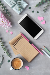 Springtime flat lay with pearl hyacinth flowers, eucalyptus, mobile phone, notebook and gift postcards on stone