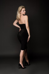 Fototapeta na wymiar beautiful elegant girl in black dress posing on black