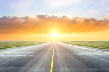 Asphalt road with a yellow dividing strip in the evening during sunset.
