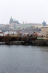 Obraz premium Snowy foggy Prague Lesser Town with gothic Castle above River Vltava, Czech republic