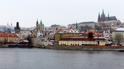 Snowy foggy Prague Lesser Town with gothic Castle above River Vltava, Czech republic