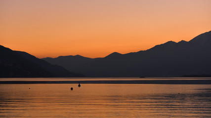 Tramonto sul lago, cielo arancione e anatre in lontananza