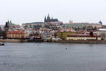 Fototapeta premium Snowy foggy Prague Lesser Town with gothic Castle above River Vltava, Czech republic