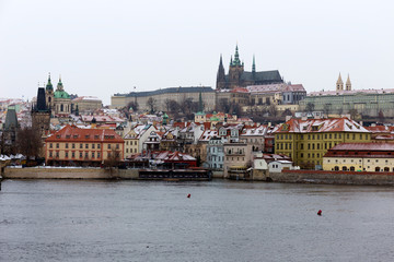 Snowy foggy Prague Lesser Town with gothic Castle above River Vltava, Czech republic