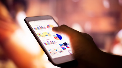 hand holding mobile phone with chart and graph screen