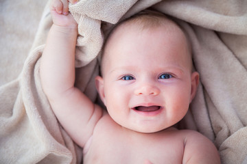 smiling baby girl lying on a beige towel