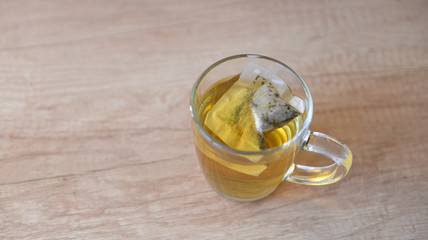 Herbal tea in a paper bag brewed in a transparent mug on a wooden table
