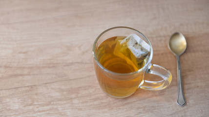 Herbal tea in a paper bag brewed in a transparent mug on a wooden table