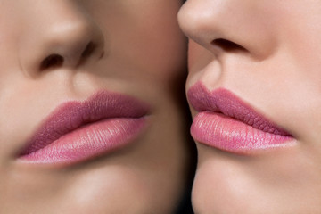 Close up of a young woman's rose colored lips reflecting in a mirror.