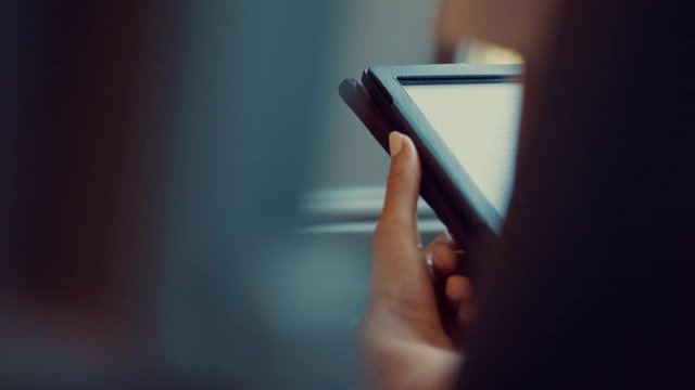 woman reading book on ebook reader while riding on train