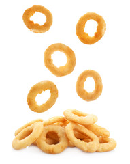 Delicious fried crispy onion rings falling in heap on white background