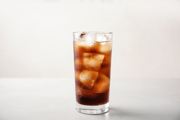 Fototapeta na wymiar Glass of refreshing cola with ice on white table
