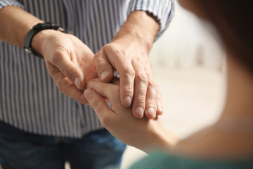 Fototapeta premium Man comforting woman on light background, closeup of hands. Help and support concept