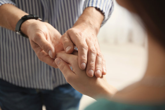 Man comforting woman on light background, closeup of hands. Help and support concept