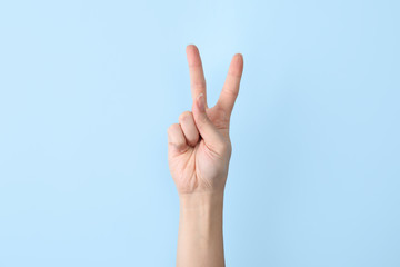 Woman showing V letter on color background, closeup. Sign language - obrazy, fototapety, plakaty