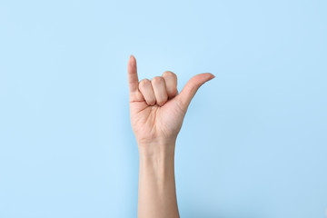 Woman showing Y letter on color background, closeup. Sign language