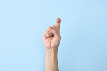 Woman showing X letter on color background, closeup. Sign language