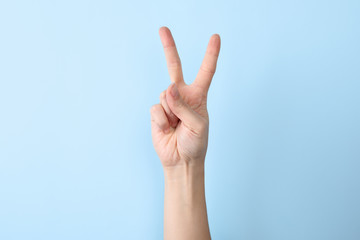 Woman showing number two on color background, closeup. Sign language