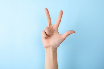 Woman showing number three on color background, closeup. Sign language