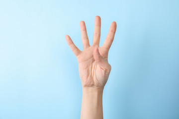 Woman showing number four on color background, closeup. Sign language