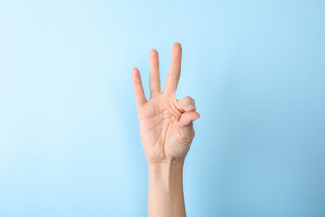 Woman showing number nine on color background, closeup. Sign language