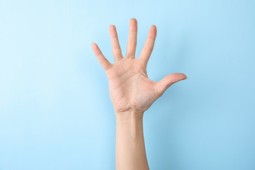 Woman showing number five on color background, closeup. Sign language