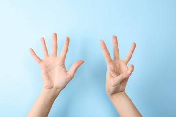 Woman showing sign eight on color background, closeup. Body language