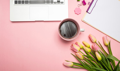 Pink tulips bouquet and computer laptop on pink pastel background, top view, copy space