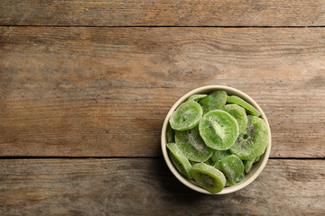 Bowl of dried kiwi on wooden background, top view with space for text. Tasty and healthy fruit