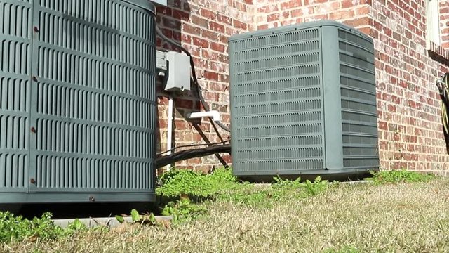 Dolly shot of air conditioner units next to brick home