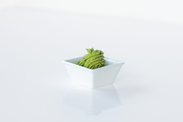 Wasabi portion for sushi and rolls in a square bowl isolated on a white background. Japanese spice wasabi. Close up. Asian hot sauce. For Menu, Mobile, Web, Decor, Print Products, Applications. 
