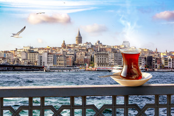 A cup of Turkish tea in a traditional glass against the background of the Golden Horn and the Galata Tower in Istanbul