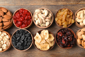 Composition of different dried fruits and nuts on wooden background, top view