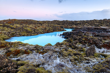 Beautiful volcanic terrain with black volcanic rocks and turquoise water at blue lagoon geothermal spa in Iceland