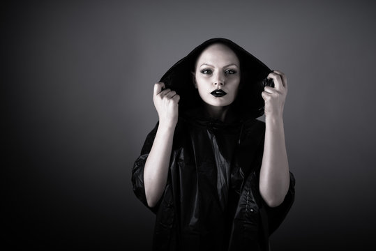 Emotive photo of a beautiful bald woman in a black raincoat with the hoods on.