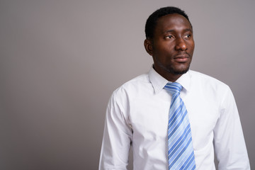 Young handsome African businessman against gray background