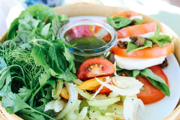 Close up of a fresh, organic garden salad with herbs, rocket, parsley, tomatoes, celery, fennel and mozzarella.