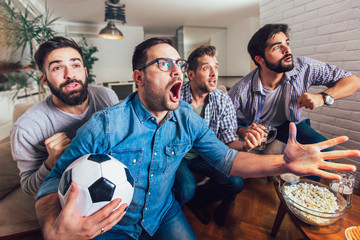Fototapeta Men watching sport on tv together at home screaming cheerful. obraz