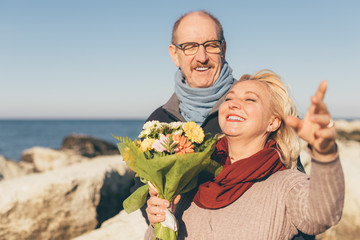 Portrait of happy smiling senior couple with bouquet of flowers - concept of love, family and...