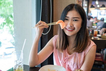 Beautiful asian woman eating sashimi, Japanese food.