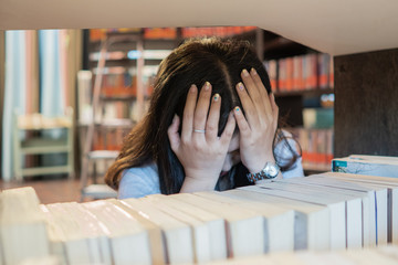 Student woman in bad mood failed and has problem in library. Having headaches.