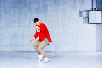 Young man dancing break dance. Young stylish guy in trendy apparel dancng hip-hop against grey background.