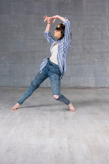 Young female dancer in movement. Modern style dancer practicing dance element on studio background.