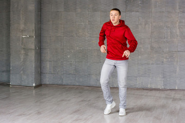 Obraz na płótnie Canvas Young dancer practicing dance element. Young handsome hip hop dancer dancing contemporary urban street dance on grey wall background.
