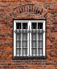 Fototapeta na wymiar Vergittertes Fenster an einem Backsteinhaus