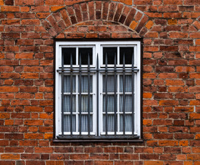 Vergittertes Fenster an einem Backsteinhaus