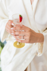 A bride holding a glass of champagne with strawberry in hands