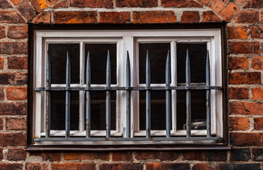 Vergittertes Fenster an einem Backsteinhaus